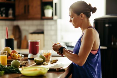 Athletic person slicing fruit while preparing smoothie in the kitchen.